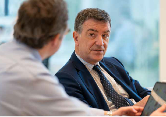 A person in a suit talking to another person
Description automatically generated with low confidence